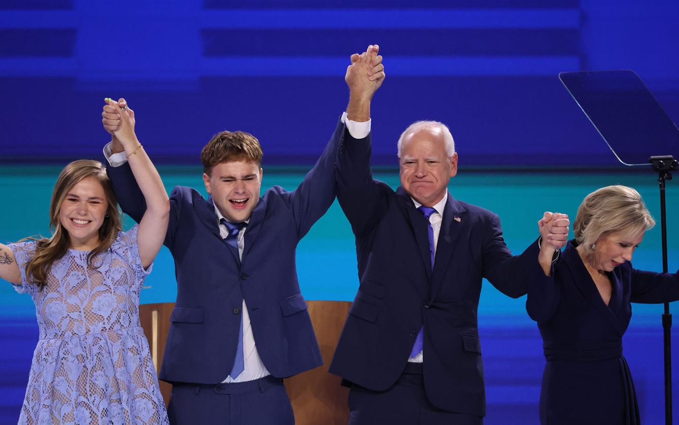 Tim Walz waves to the crowd with his family after speaking at the DNC