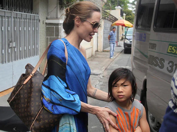 Angelina Jolie, left, and her adopted son Pax Thien get on a minivan to leave a Vietnamese restaurant in Ho Chi Minh City, Vietnam