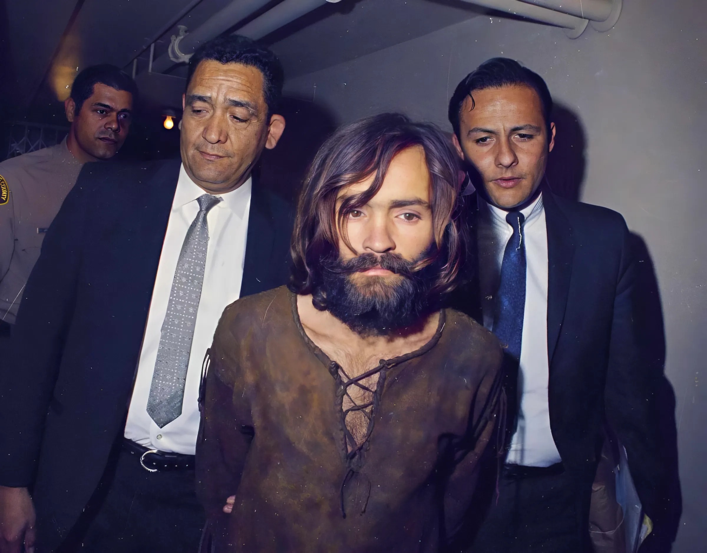 Charles Manson is escorted to his arraignment on conspiracy-murder charges