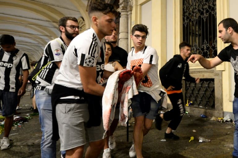 AFP / Massimo PINCA Juventus supporters carry an injured woman in Piazza San Carlo in Turin after a stampede in the fanzone where fans were watching the Champions League Final between Juventus and Real Madrid on a giant screen, on June 3, 2017